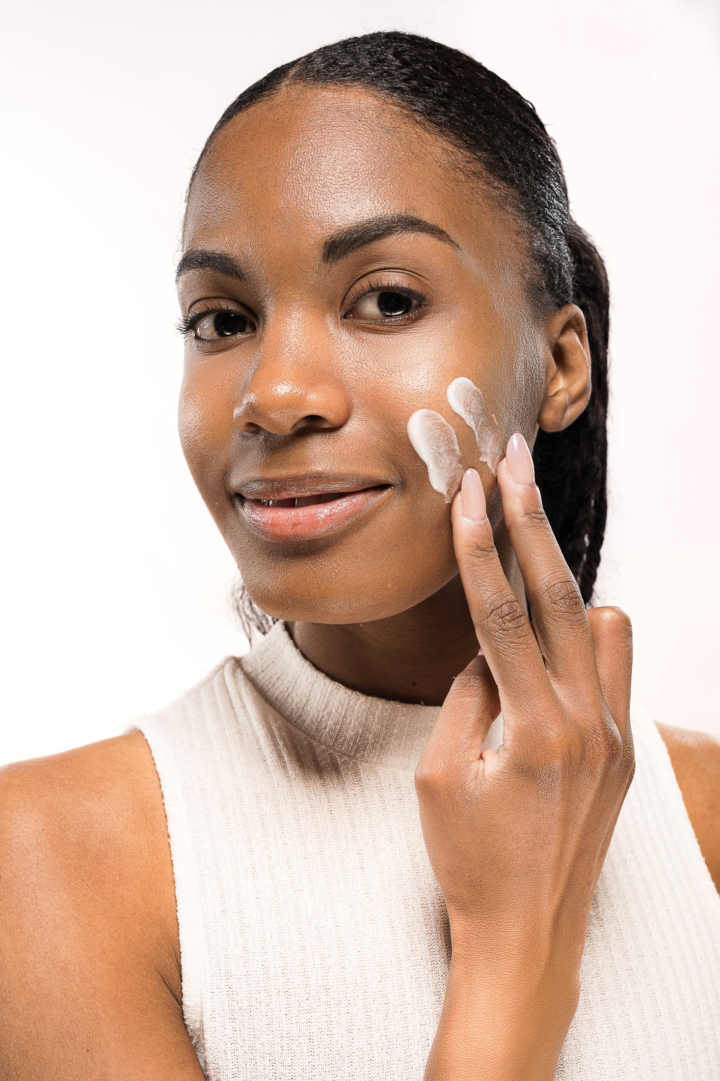 Donna sorridente applica una crema idratante sul viso